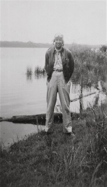 Lieutenant Wayne Proulx wearing his leather flight jacket and goggles standing next to a lake at Camden South Carolina
